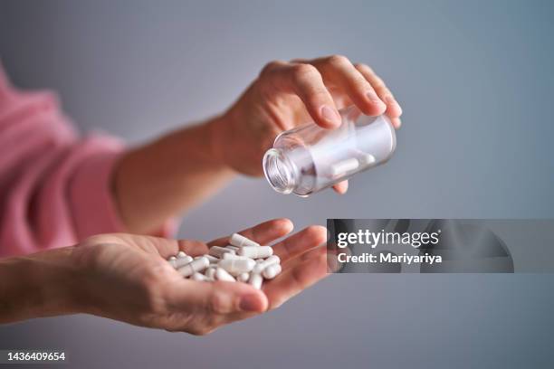 the girl pours the capsules of the drug into her hand. - antibiotikaresistent stock-fotos und bilder