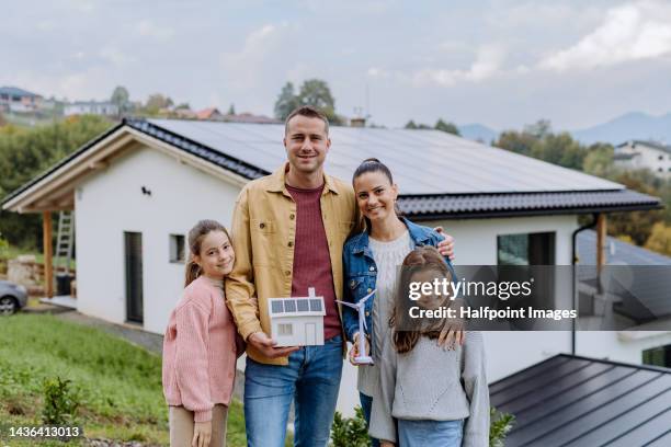 cheerful family holding model of house and model of wind turbine. - fuel and power generation stock-fotos und bilder