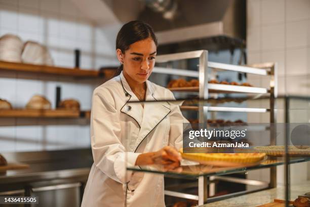 young hispanic baker arranging the pastry - pastry chef stock pictures, royalty-free photos & images