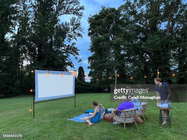 man setting up projector for outdoor movies - backyard picnic stockfoto's en -beelden