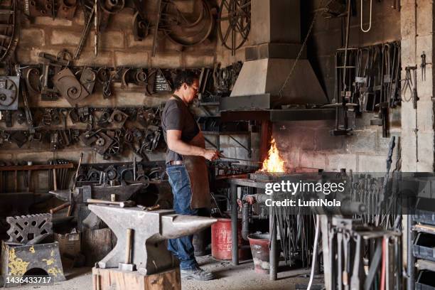 mann in der metallwerkstatt, schmiedearbeiter handwerker in der schmiede mit hammer und stahlamboss schweißwerkzeuge im feuer. eisenschmiedschweißer, schmelzwerkzeug und ausrüstung in der gießerei für die industrielle industrie - blacksmith sparks stock-fotos und bilder