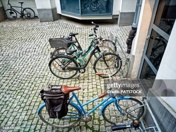 city bikes parked in paved yard. - courtyard stock-fotos und bilder