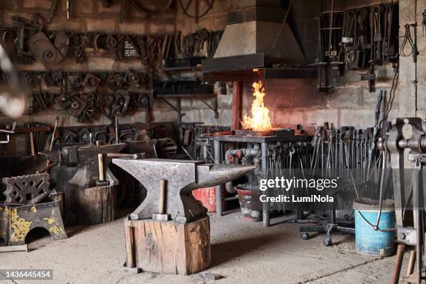 interior, manufacturing and industrial with blacksmith workshop room for construction, engineering and metal work. welding, maintenance and steel in factory warehouse with anvil, forge and tools - smid stockfoto's en -beelden