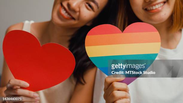 young beautiful asia lesbian couple ladies in bedroom. happy girls smile looking at camera show rainbow heart lgbt community symbol together on bed at home. - equality logo stock pictures, royalty-free photos & images