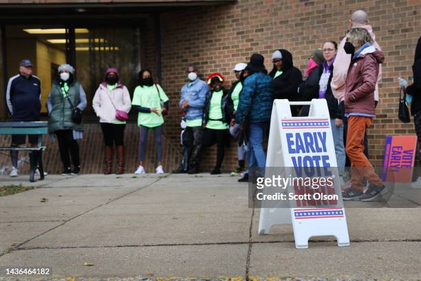 People wait in line outside a polling place at the start of early voting on October 25, 2022 in Milwaukee, Wisconsin. Early voting for the mid-term...