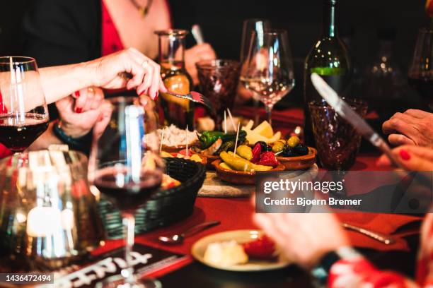 people eating tapas at a tapas bar with food and drinks on the table - patatas bravas stockfoto's en -beelden