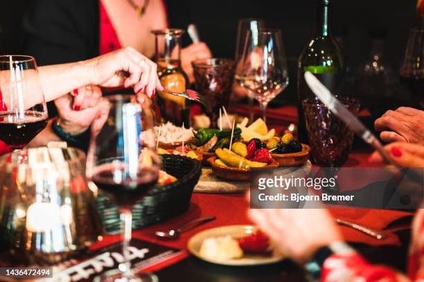 people eating tapas at a tapas bar with food and drinks on the table - patatas bravas stock pictures, royalty-free photos & images