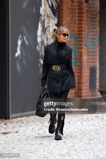 Influencer Gitta Banko wearing a black turtleneck pullover by Gitta Banko, a black blazer by H&M, black skinny pants with slits by The Attico, a...