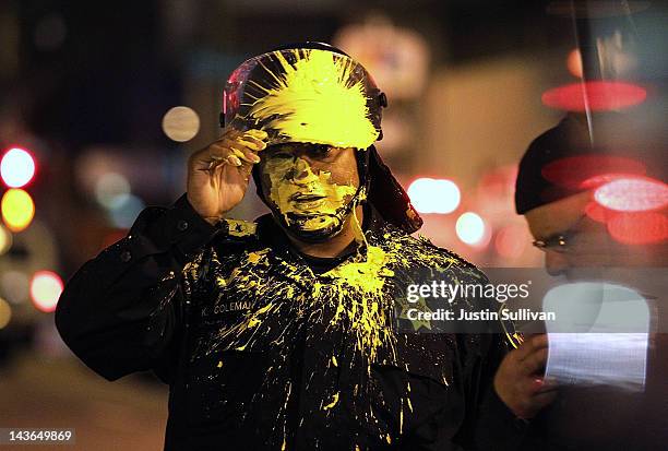 An Oakland police officer pauses after being hit in the face with paint as officers advanced on Occupy protesters blocking an intersection during a...