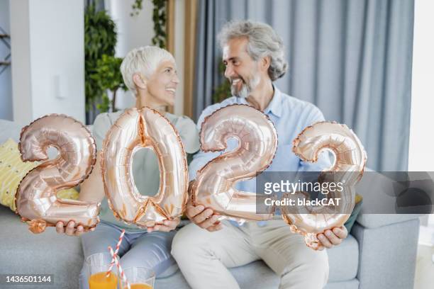 seniorenpaar hält ballonnummern als symbol für 2023. jahr - 50 year old black woman stock-fotos und bilder