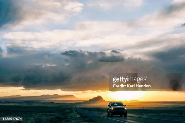 an suv on a desert road in new mexico at sunset - 4x4 desert stock-fotos und bilder