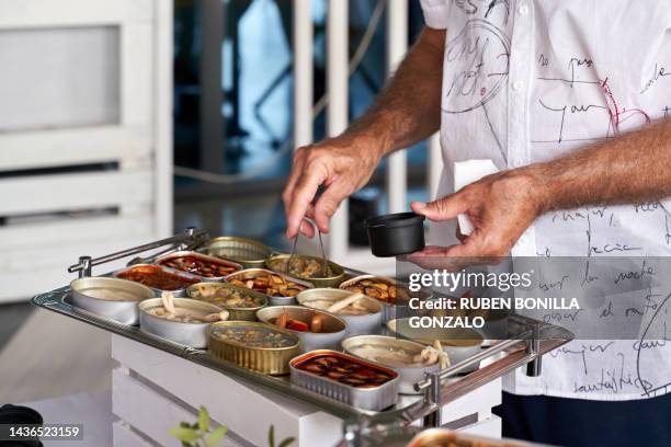 side view of a caucasian person taking canned seafood from cans on tray ready to be eating. food and drink concept. - producto enlatado fotografías e imágenes de stock