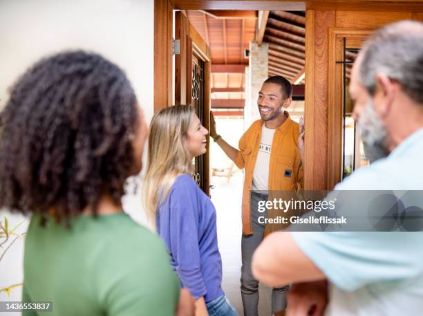 friends arriving at a man's home for a get-together - man opening door woman bildbanksfoton och bilder