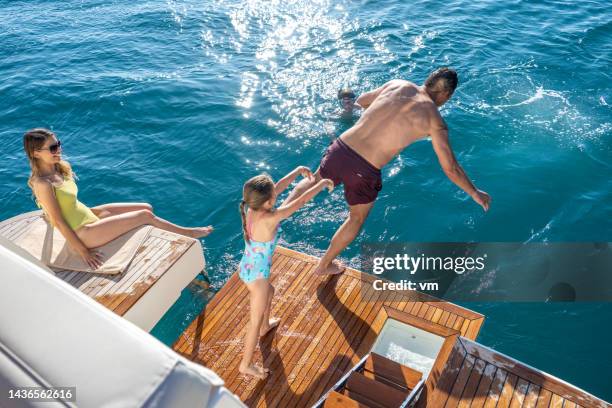 family with children enjoying sunny day in water during yacht cruise - family yacht stock pictures, royalty-free photos & images