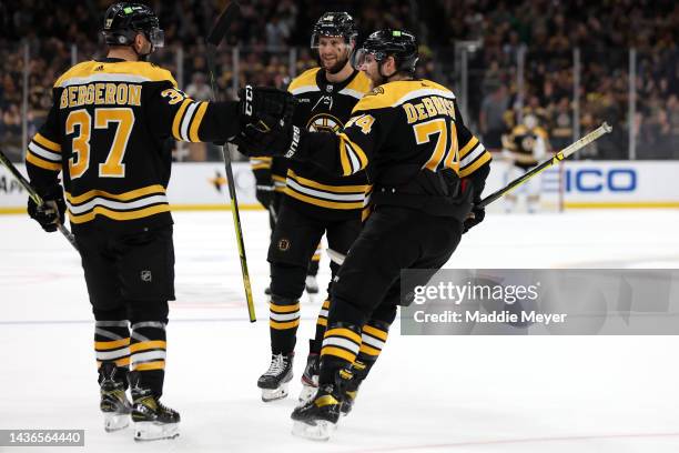 Patrice Bergeron of the Boston Bruins celebrates with Jake DeBrusk and Pavel Zacha after scoring a goal against the Dallas Stars during the third...