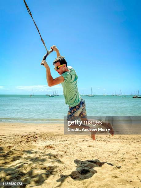 person on rope swing, beach island blue sky - jumping australia stock-fotos und bilder