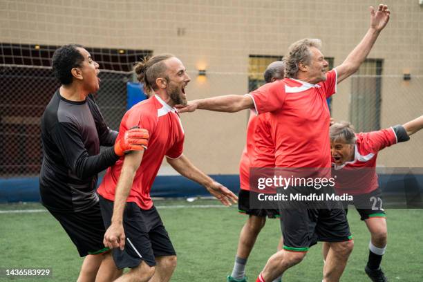 soccer team wearing red sportwear running and celebrating victory - sports league stock pictures, royalty-free photos & images