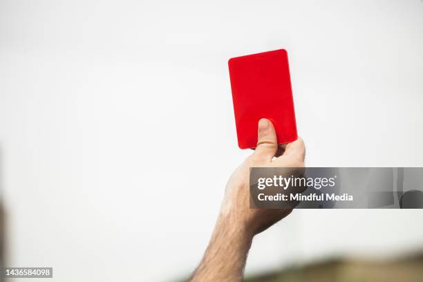 close-up view of football referee's hand holding red card - referee stockfoto's en -beelden