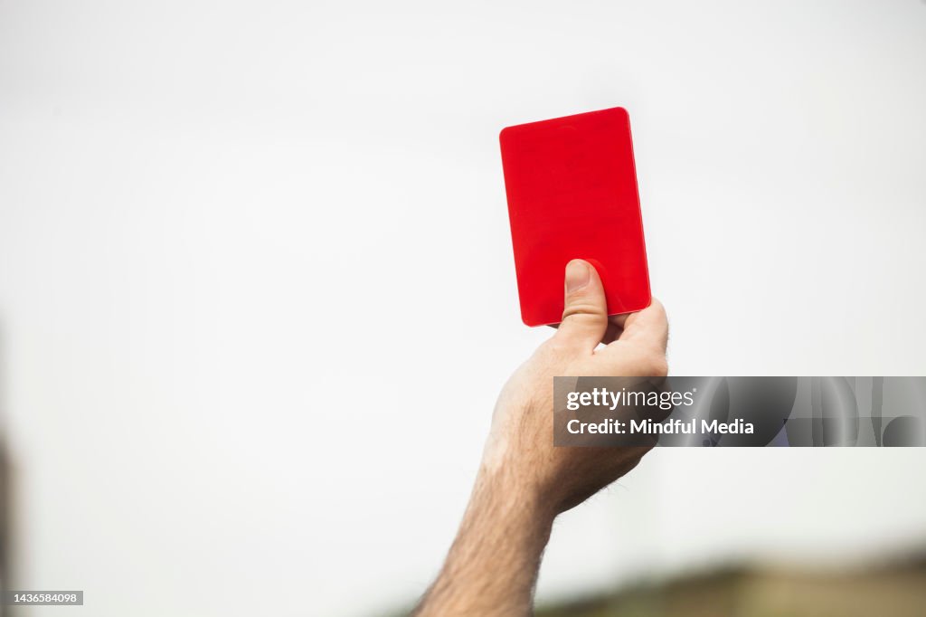 Close-up view of football referee's hand holding red card