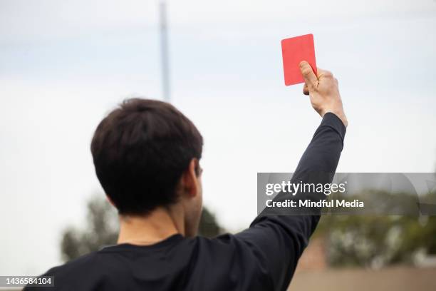 männlicher fußballschiedsrichter hebt während des spiels eine rote karte - punktrichter stock-fotos und bilder