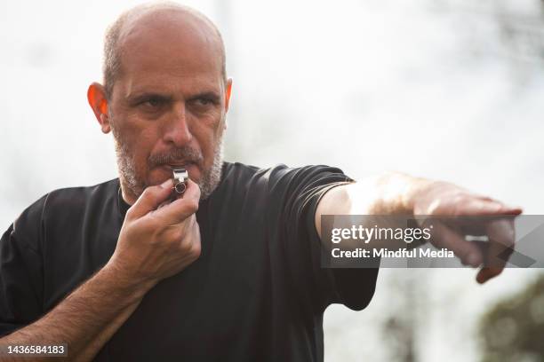 amateur football game referee blowing whistle while signaling at point of foul - blame game stock pictures, royalty-free photos & images