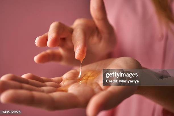 a girl in pink touches a gel cosmetic in her palm with her finger. - retinol stock pictures, royalty-free photos & images