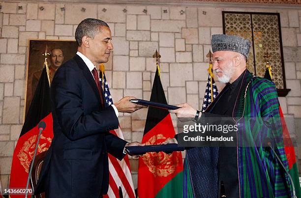 In handout image released by the Afghan Presidents Office, US President Barack Obama exchanges documents with Afghanistan President Hamid Karzai ,...