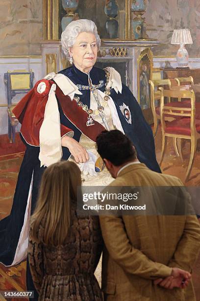 Visitors look at a painting of Queen Elizabeth II during a photocall for the Royal Society of Portrait Painters exhibition at the Mall Galleries on...