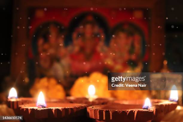 lit clay diya against bokeh/goddess lakshmi, saraswati, lord ganesha  background-diwali/deepavali festival - laxmi ganesh stock pictures, royalty-free photos & images