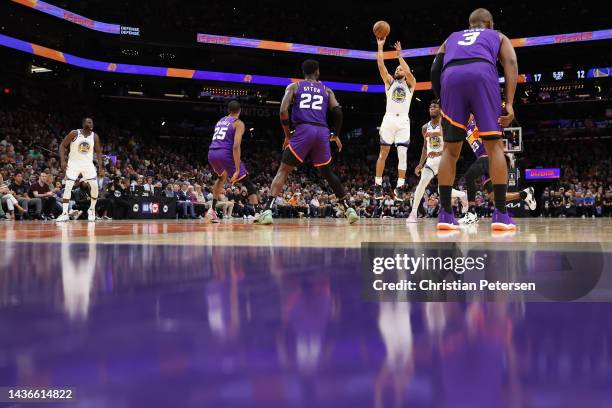 Stephen Curry of the Golden State Warriors puts up a three-point shot over Deandre Ayton of the Phoenix Suns during the second half of the NBA game...
