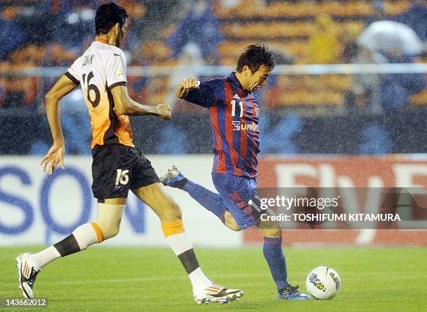 Tokyo forward Kazuma Watanabe shoots to score the goal while Brisbane Roar defender Sayed Mohamed Adnan chases him during their AFC Champions League...