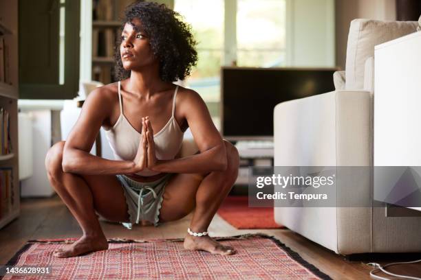 daydreaming or meditating in the garland pose (malasana) yoga prayer squat position? - dark skin tone stock pictures, royalty-free photos & images