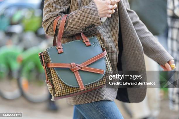 Guest wears a brown and beige houndstooth print pattern blazer jacket, gold rings, a beige and yellow houndstooths print pattern in coated canvas and...