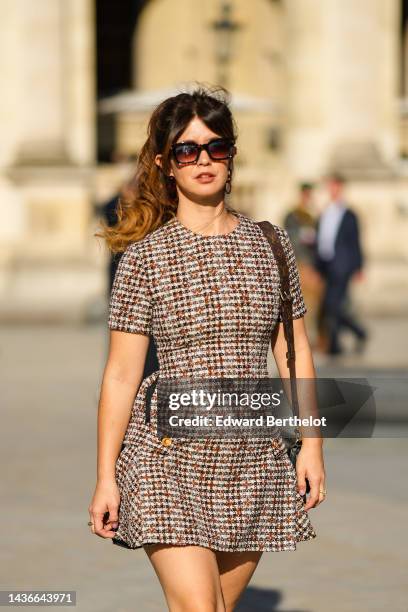 Guest wears black sunglasses, a white with embroidered dark brown and black checkered print pattern / tweed / short sleeves / short dress, a brown LV...