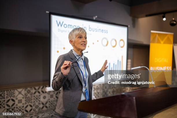 geschäftsfrau hält eine rede vor publikum im konferenzraum eines hotels - women podium stock-fotos und bilder