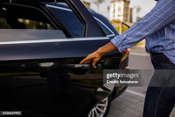 young black woman entering a taxi after ordering a ride via mobile app on smart phone - open car door stock pictures, royalty-free photos & images
