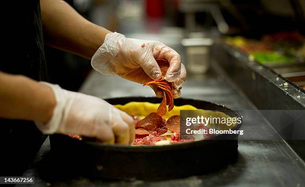 An employee prepares a deep dish pizza at Gino's East restaurant in Chicago, Illinois, U.S., on Wednesday, April 18, 2012. U.S. Restaurant-industry...