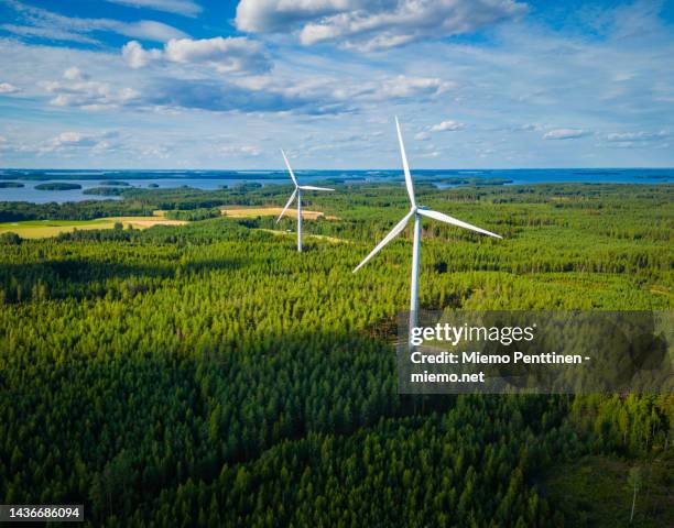 aerial view of wind turbines in a forest next to a large lake in finland on a sunny summer day - finland landscape stock pictures, royalty-free photos & images