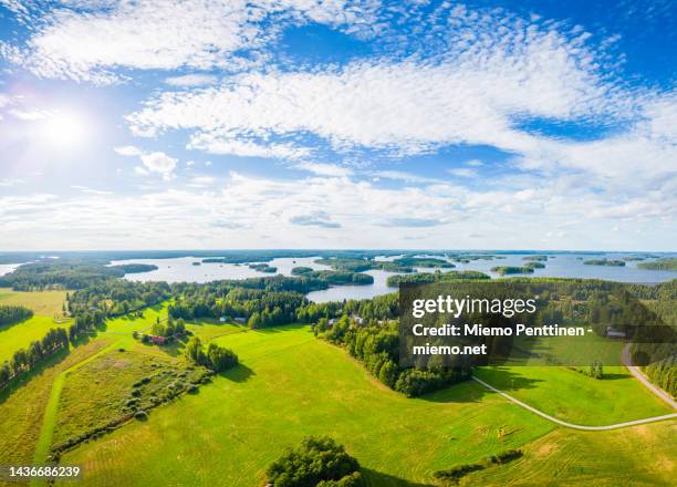aerial landscape of agricultural fields, farm houses, small forests and the lake saimaa on a sunny summer day in finland - lappeenranta stockfoto's en -beelden
