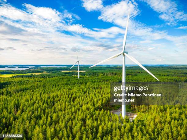 aerial view of wind turbines in a forest next to a large lake in finland on a sunny summer day - lappeenranta stockfoto's en -beelden