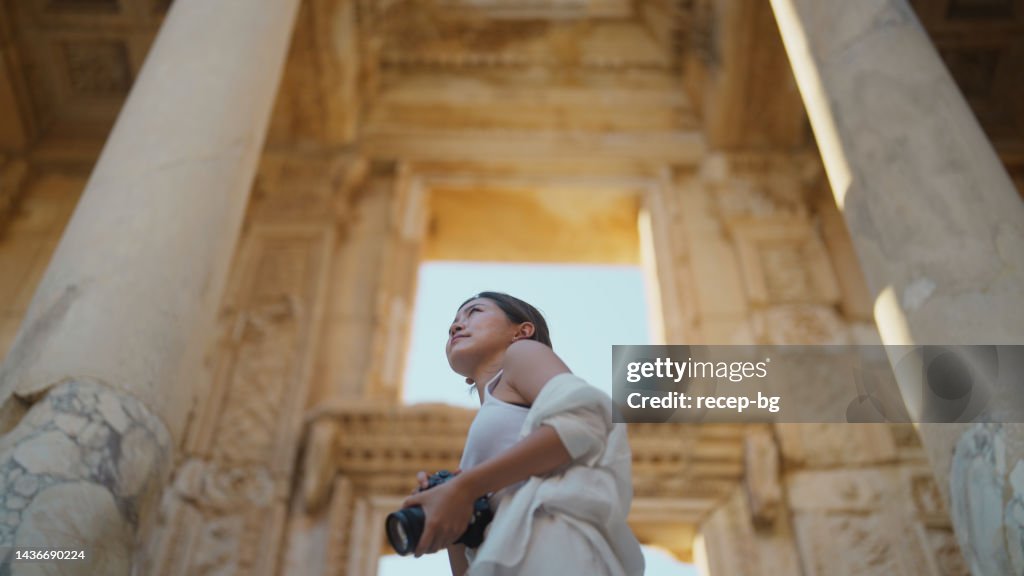 Young female tourist taking photos and videos in historical ancient town