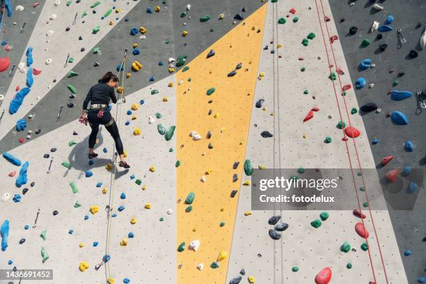 mulher em equipamentos de segurança e treinamento de arreios na parede de escalada artificial - bouldering - fotografias e filmes do acervo