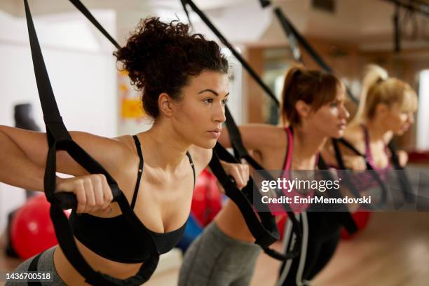 suspension training- three young women doing arm exercises - suspension training stockfoto's en -beelden