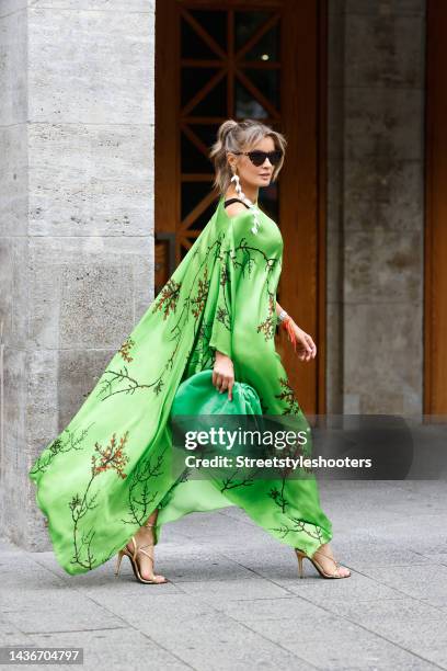 Influencer Gitta Banko wearing a green long dress with floral print by Simone Bruns, a green bag by Simone Bruns, white les pois flower garland...