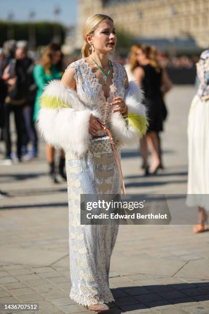 Guest wears diamonds and green pendant earrings, a white and green pearls long necklace, a silver sequined and pearls V-neck / sleeveless / long tube...