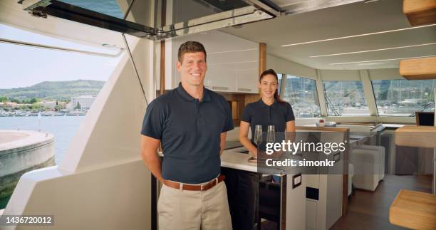 yacht stewardess and skipper standing in yacht - luxury yacht stock pictures, royalty-free photos & images