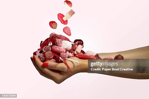 hand holding a bunch of red candy falling - handvol stockfoto's en -beelden