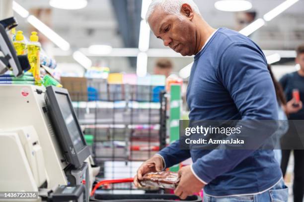 mature hispanic man standing at a self checkout counter in the store - self discipline stockfoto's en -beelden