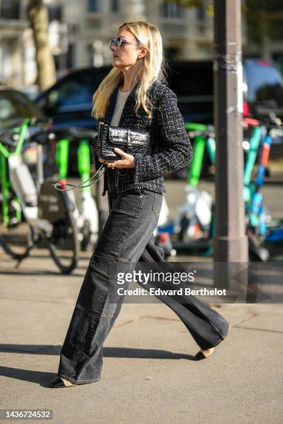 Guest wears sunglasses, a beige sweater, a black and neon yellow tweed jacket from Chanel, a black shiny leather crocodile print pattern handbag,...