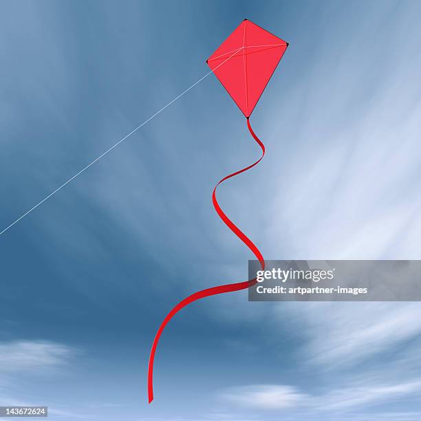 red childrens kite flying against a blue sky - kite toy foto e immagini stock